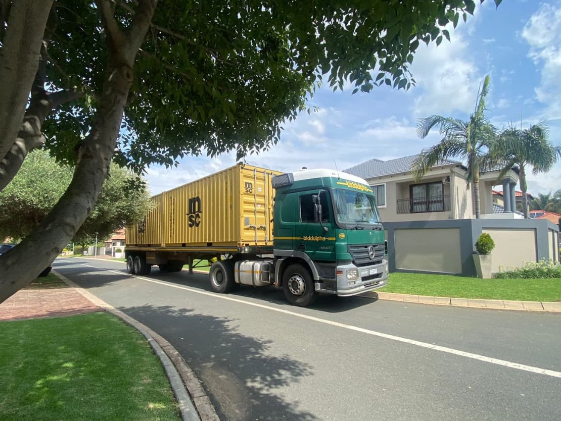 A Biddulphs truck carrying a shipping container on a residential street